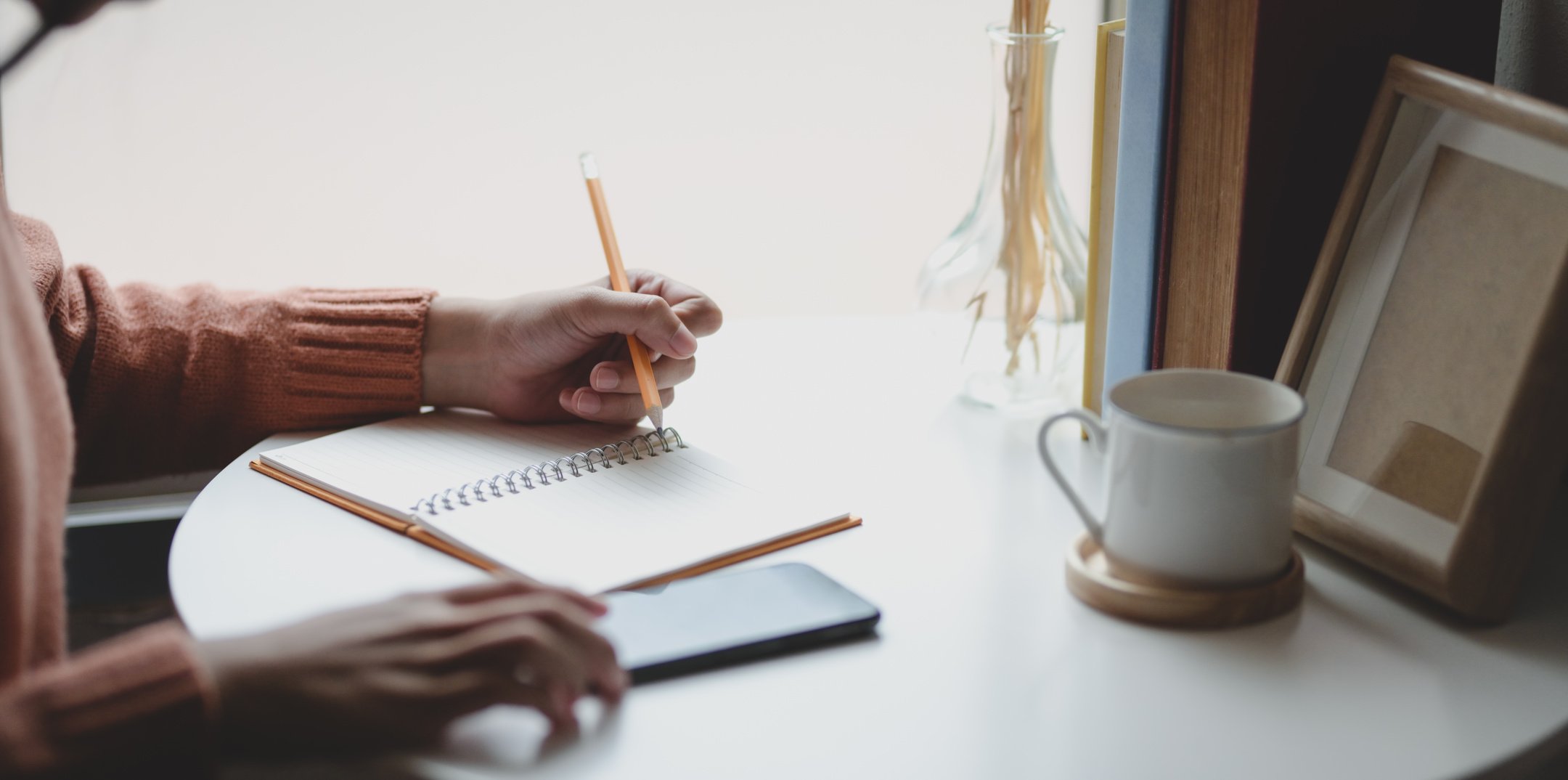 Woman writing plans in notebook at home